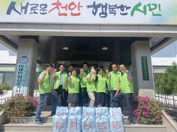 천안기초푸드뱅크 정옥선 대표가 지난 2일 천안시 수신면 이관희 면장에게 긴급식품꾸러미인 ‘이머전시팩’을 전달하고 기념촬영을 하고 있다.